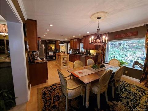 Dining area with a chandelier and a large picture window, open to the kitchen.