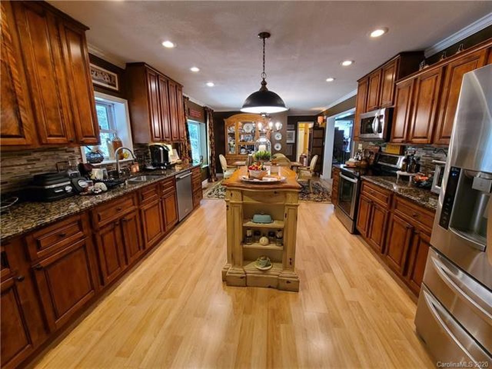 Kitchen with wood cabinetry, granite counters, stainless steel appliances, pendant lights and a center island.