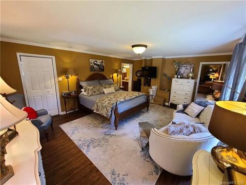 Large bedroom with wood floors, an area rug and a sitting area.