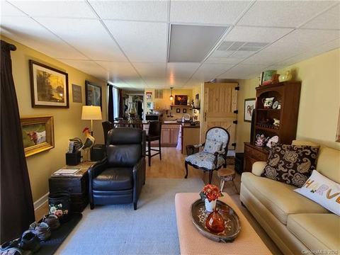 Lower-level living room with a sofa, leather armchairs and a cabinet, opening to the rooms beyond.