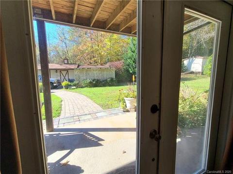 View through the lower-level glass door to a covered patio and a brick walkway leading to the outbuilding.