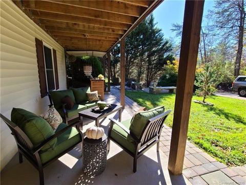 Covered patio with cushioned chairs beside the lawn.